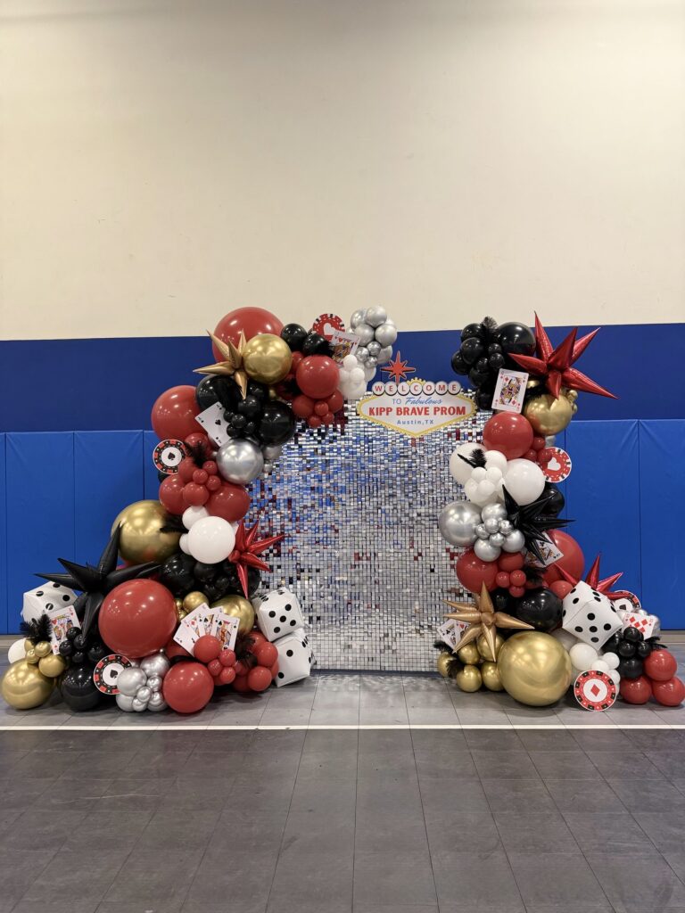 Red, black and gold casino themed balloon backdrop with dice and playing card balloons in Austin, TX