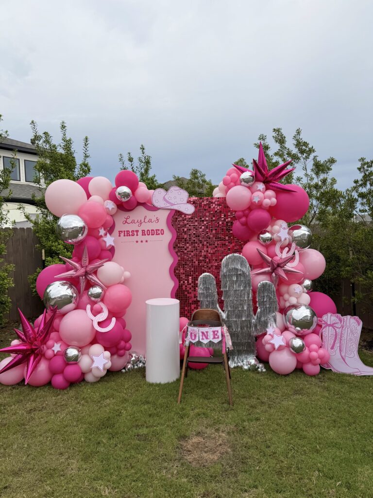 Hot pink and silver balloon backdrop with a sequin wall for a first rodeo themed first birthday in Austin, TX
