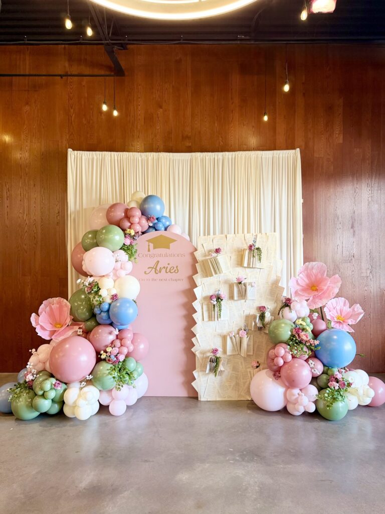 Pastel balloon garland with oversized paper flowers for a first birthday in Austin, TX