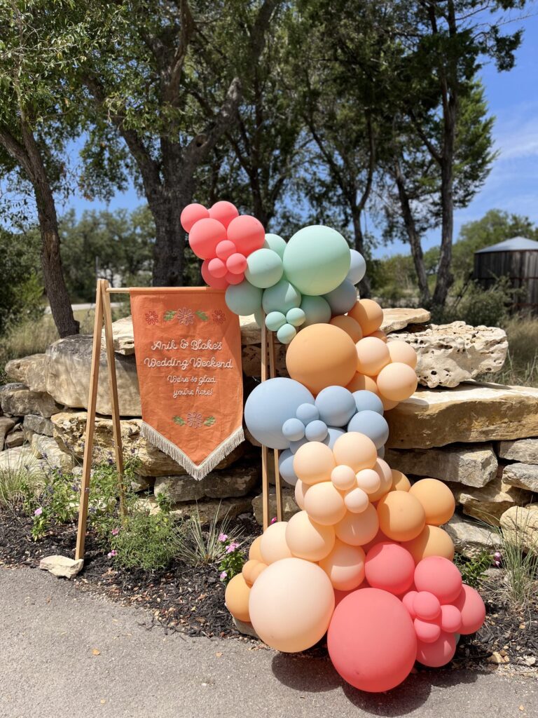 Terracotta, sage and coral balloon garland cascading over limestone rocks in Austin, TX