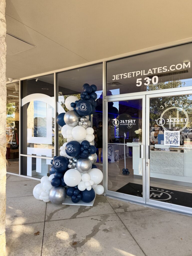 Navy, silver and white balloon garland along the storefront of a Pilates studio in Austin, TX