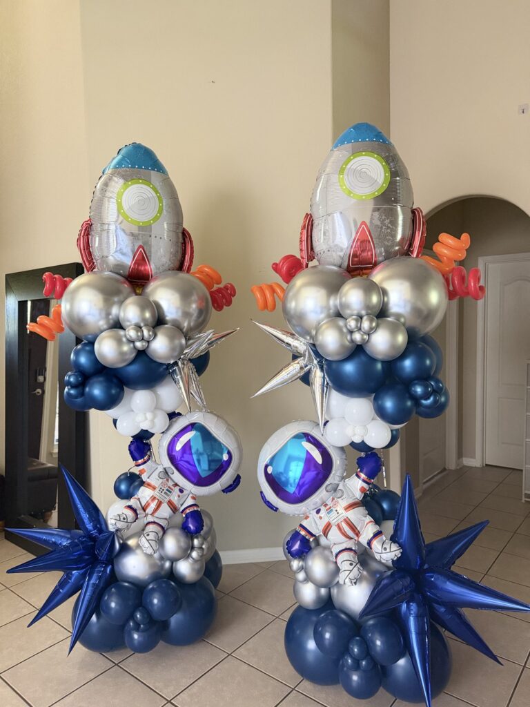 Navy and silver freestanding balloon columns topped with rocket and astronaut balloons in Austin, TX